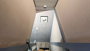 A narrow stairway with wooden steps and a brick wall with a framed picture.