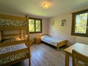 Een kamer met stapelbedden, een enkele bed, een bureau en twee ramen.