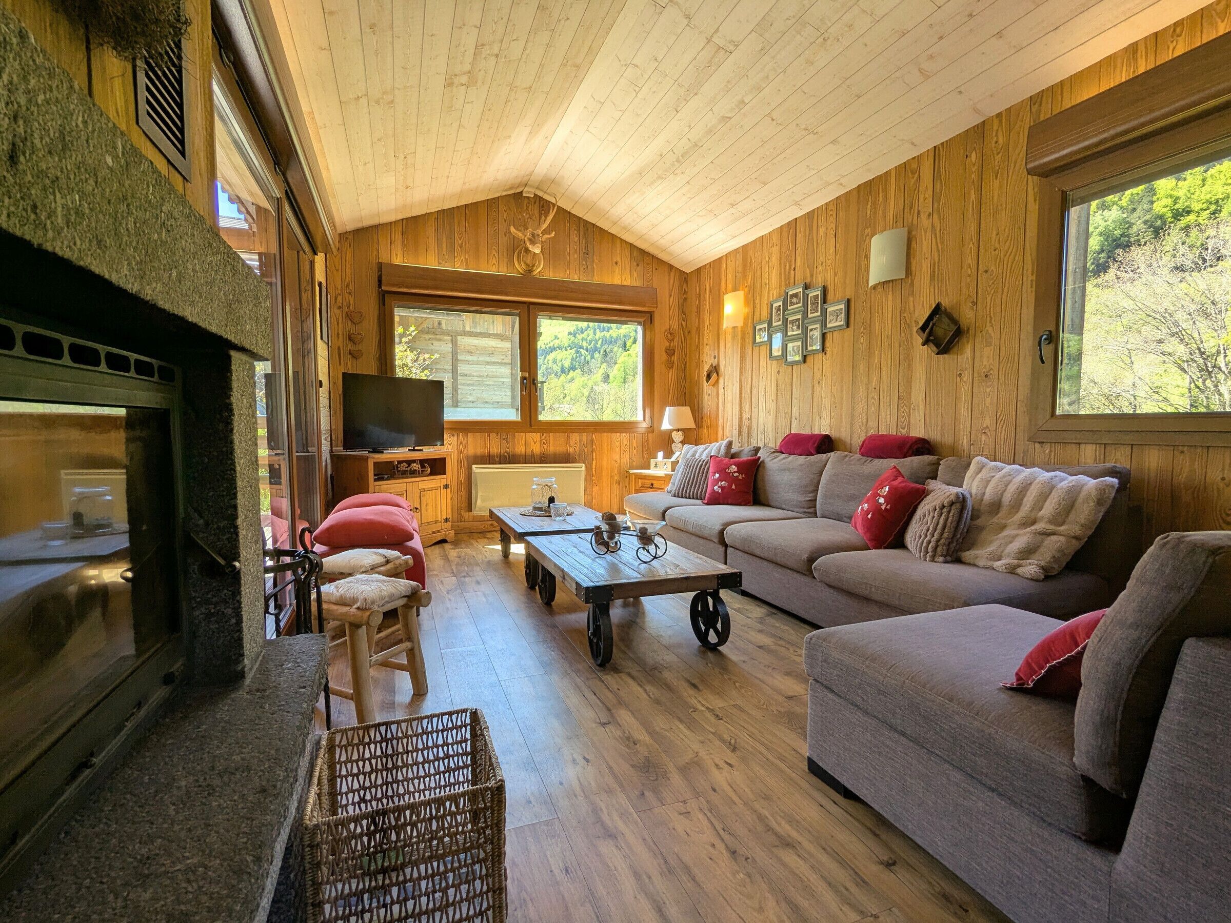 A cozy living room with a fireplace, wooden walls, a sofa, and a television.