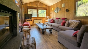 A cozy living room with a fireplace, wooden walls, a sofa, and a television.