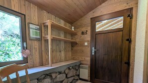 A wooden interior with a stone counter, a wooden door, and a chair.