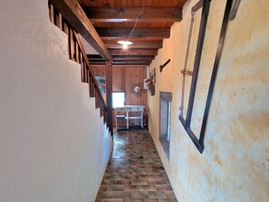 A narrow hallway with a wooden staircase on the left and a white wall on the right.