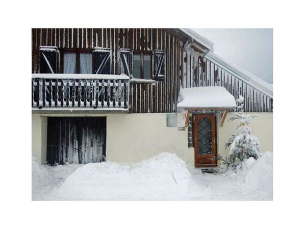 A two-story building with a wooden balcony and a snow-covered entrance.