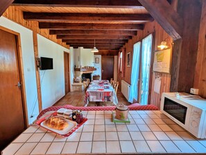 A cozy dining area with a long table set for a meal, a microwave, and a fireplace in the background.