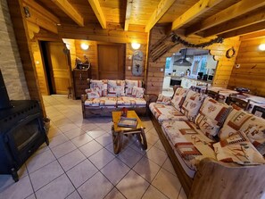A cozy log cabin interior with a fireplace, a sofa set, and a dining area.