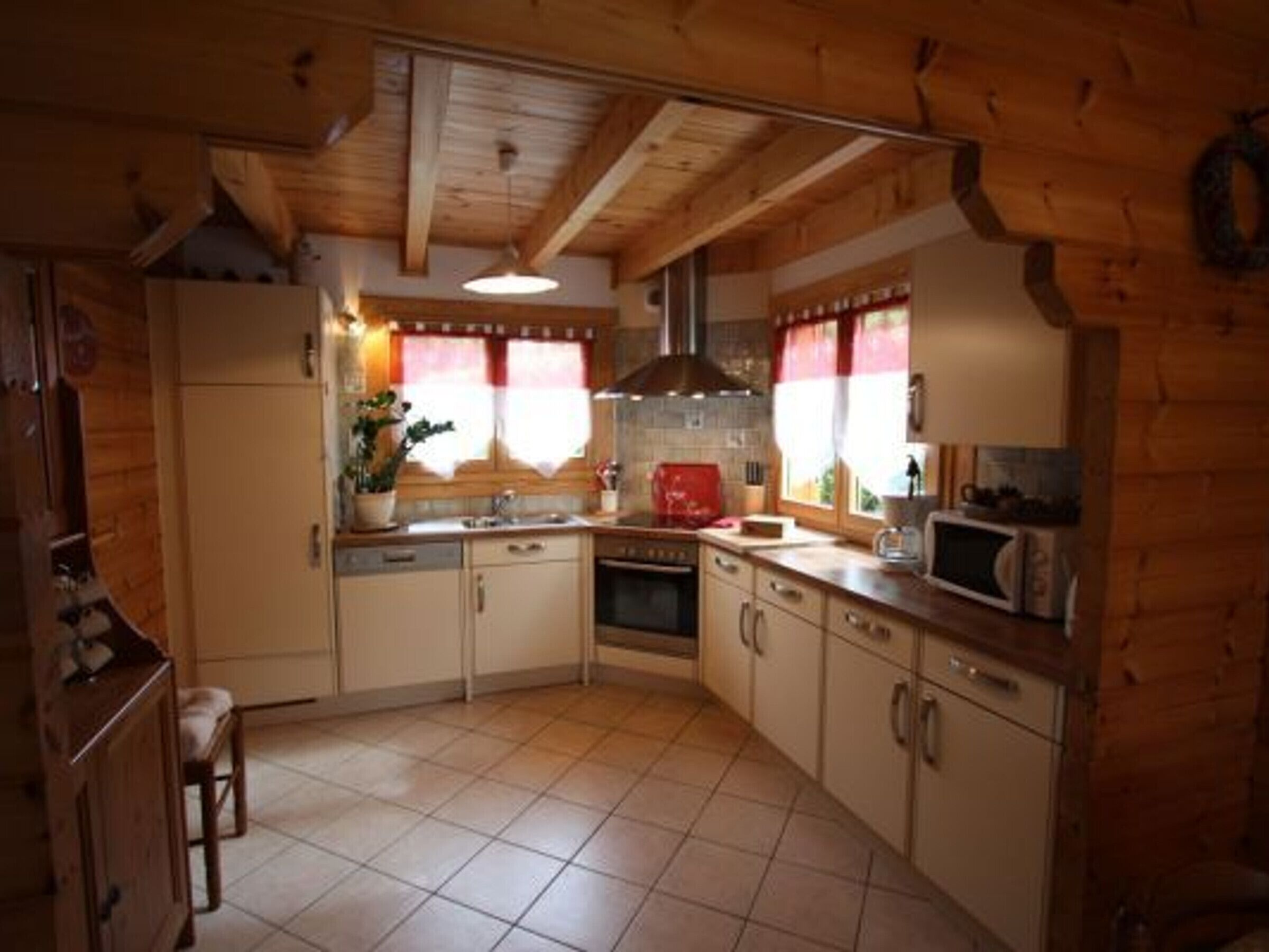 Uma cozinha compacta com armários de madeira, piso ladrilhado, forno embutido e micro-ondas.