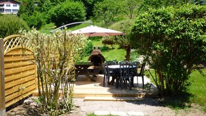A patio area with a brick oven, outdoor seating, and a wooden gate.