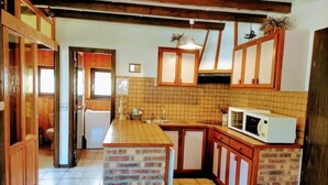 A kitchen with wooden cabinets, a tiled backsplash, and a brick island.