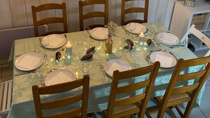 A dining table set for six with wooden chairs, a decorative vase, and a candle.