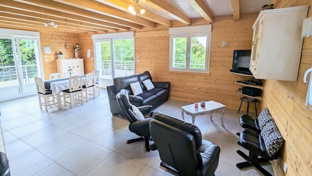 A spacious living area with a wooden interior, a sofa, a coffee table, and a television mounted on the wall. - Spacious cottage with all comforts, Vosges (Anould)