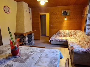 Une pièce chaleureuse avec une cheminée, une nappe à motifs et un lit recouvert d’une couvre-lit à fleurs.