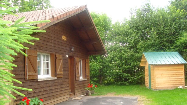 Une cabane en bois avec un toit en pente et un petit abri attenant.