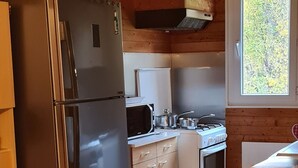 Une cuisine de taille réduite, dotée d’un réfrigérateur en acier inoxydable, d’un four à micro-ondes, d’une cuisinière et de meubles de rangement en bois.