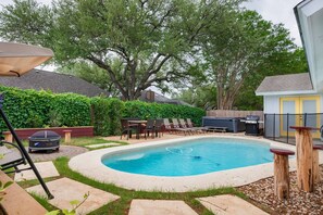 Ein Garten mit Swimmingpool, Gartenmöbeln und Grillplatz.