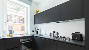 Una cocina moderna con armarios oscuros, horno empotrado, estufa a gas y un tostador.