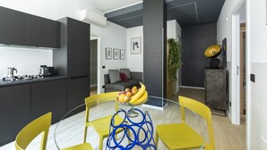 Una cocina moderna con armarios oscuros, una mesa redonda de vidrio y sillas amarillas.
