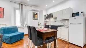 Um espaço compacto com área de jantar, cozinha e um sofá azul.