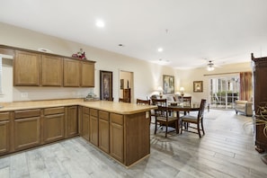 A spacious kitchen with wooden cabinets, a central island, and a dining area with chairs and a table.