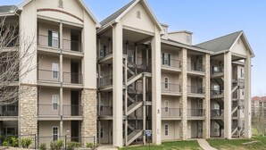 Un edificio de apartamentos de varios pisos con balcones, escaleras y fachada de piedra.