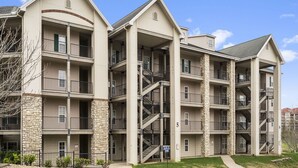 A multi-story apartment building with balconies, staircases, and a stone facade. - Walk-in 2 King Bedroom, 2 Bath Golf Condo with Covered Patio - Walk out to Pool! (Branson)