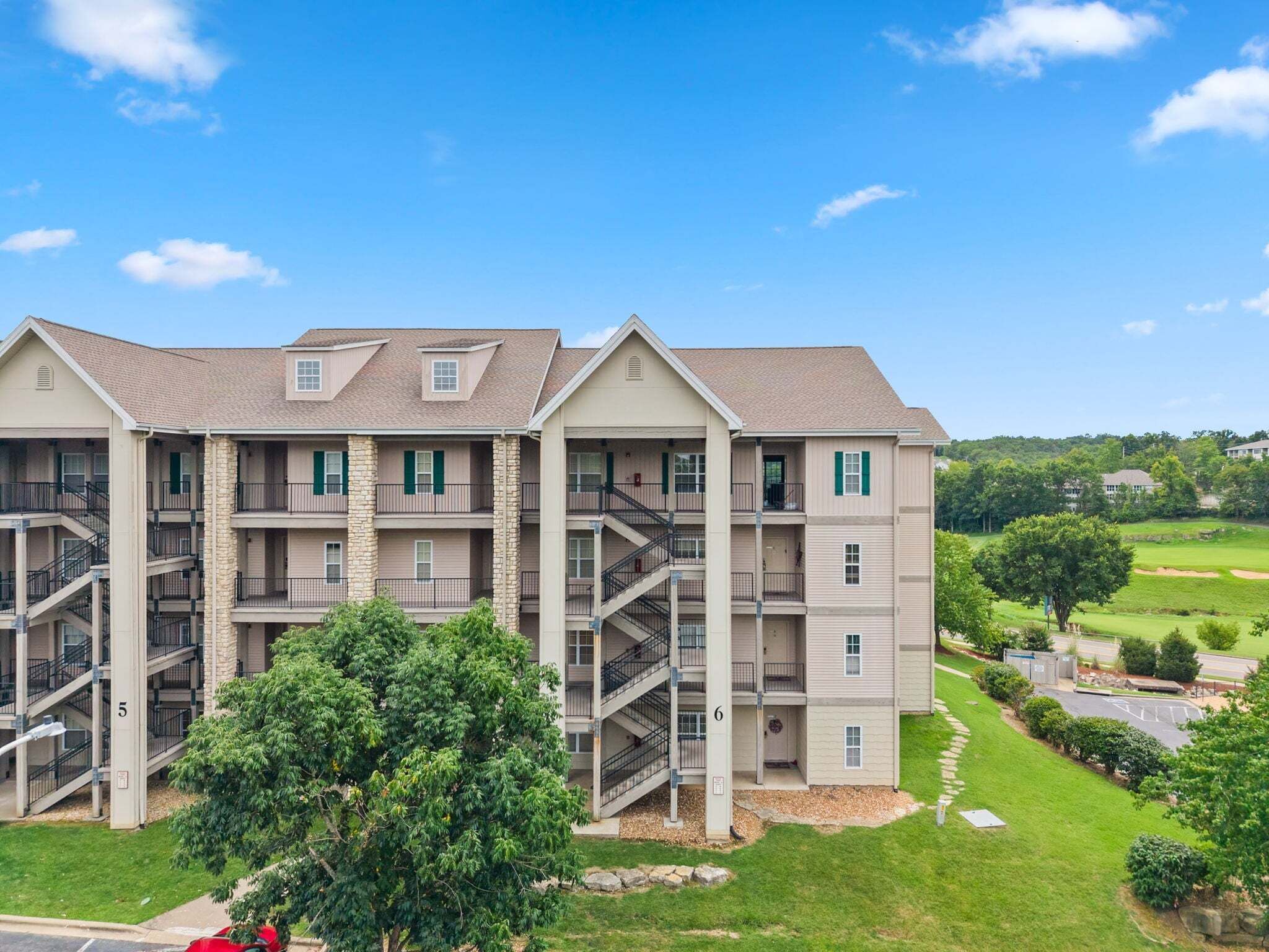 A multi-story residential building with a central staircase, balconies, and a well-maintained lawn.