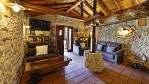 Un interior rústico con paredes de piedra, vigas de madera, una chimenea de piedra y un banco de madera.