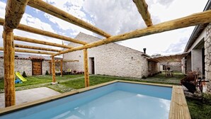 Una piscina con cubierta de madera y paredes de piedra.