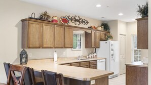 A kitchen with wooden cabinets, a central island, and a dining area with chairs. - 2 Bedroom, 2 Bath Golf Condo with Private, Covered Patio (Branson)