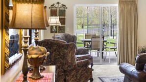 A living room with a sofa, a lamp, and a table. There is a window with curtains and a view of the outside. - 2 Bedroom, 2 Bath Golf Condo with Private, Covered Patio (Branson)