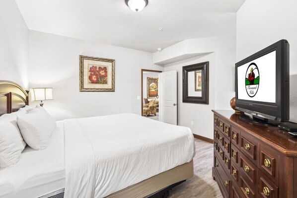 A hotel room with a bed, a dresser, a television, and framed artwork on the walls. - Branson Condo Near Attractions ⢠Pool Access ⢠Sleeps 4 (Branson)