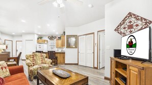 A spacious living room with a wooden coffee table, a patterned sofa, and a television on a wooden stand. - Branson Condo Near Attractions • Pool Access • Sleeps 4 (Branson)
