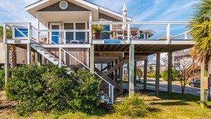 A two-story building with a balcony, a staircase, and a sign indicating a guesthouse at scotch bonnet. - Cottage at Scotch Bonnet | Walk to the Beach! (Carolina Beach)