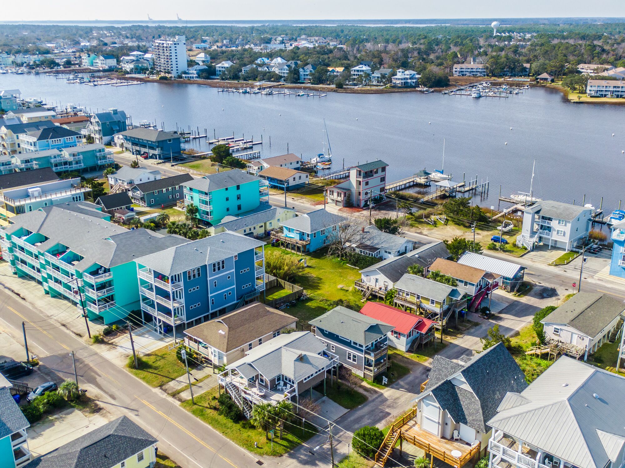 Ett flygbildsbild av ett bostadsområde vid kusten med hus, en småbåtshamn och en fyr.