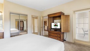 A bedroom with a large bed, a wooden dresser, a television, and a sliding glass door. - 1 Bedroom Condo + Queen Suite (Adjoined Units, Lock-Off Access) (Branson)