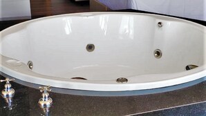 Ein Hotelzimmer mit einer großen Badewanne, zwei Betten, einem Schreibtisch und einer Tür.
