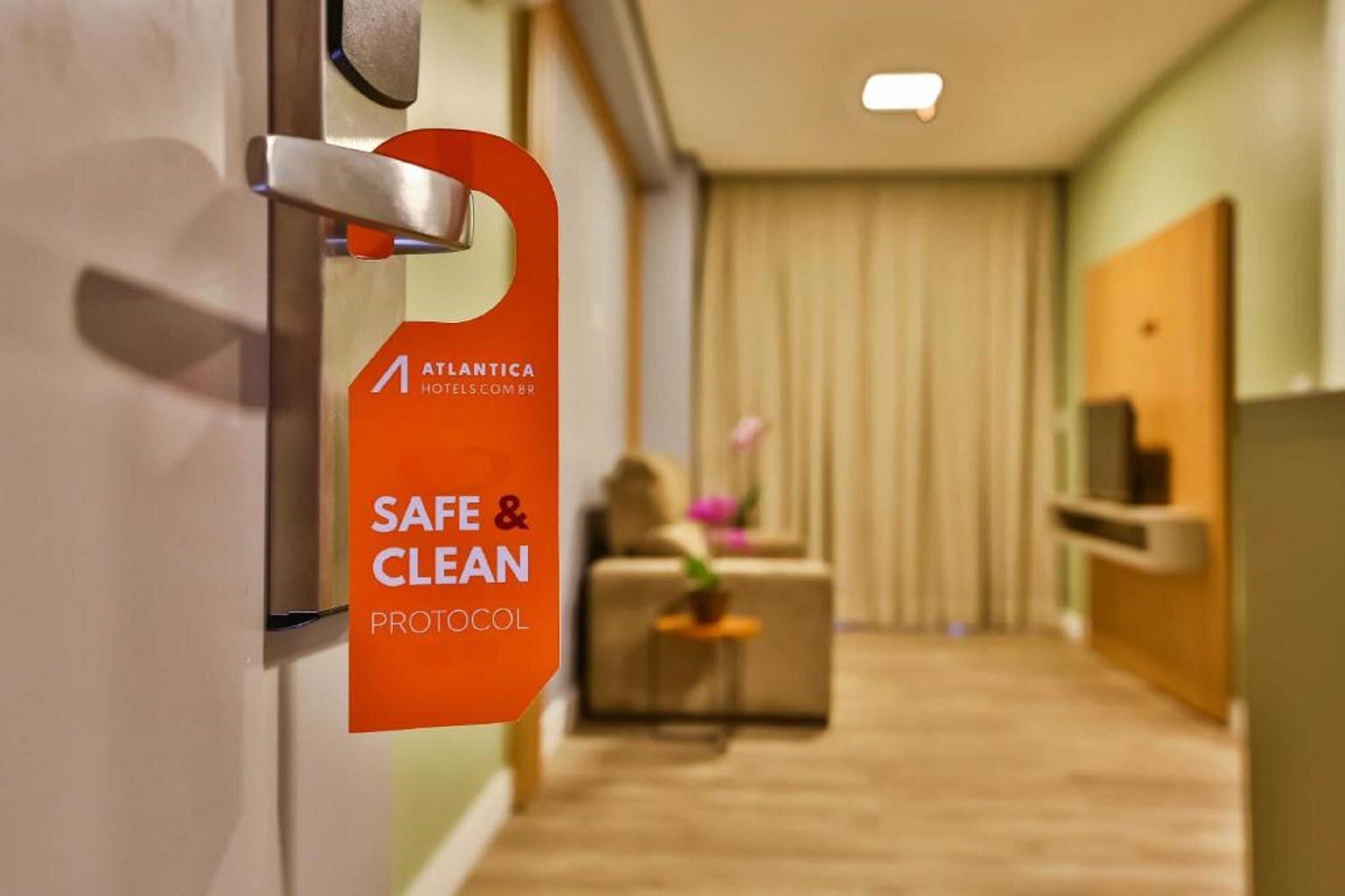 A hotel reception area with a sign indicating a 'Safe & Clean Protocol'.
