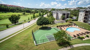 A residential area with a basketball court, a swimming pool, and a road with vehicles. - Queen Suite with Kitchenette (Branson)