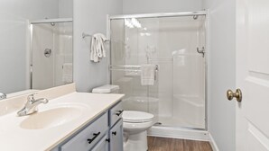 A bathroom with a white sink, toilet, and glass-enclosed shower. - Queen Suite with Kitchenette (Branson)