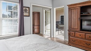 A bedroom with a large bed, a wooden dresser, and a sliding glass door leading to a balcony. - 1 Bedroom Condo + Queen Suite (Adjoined Units, Lock-Off Access) (Branson)