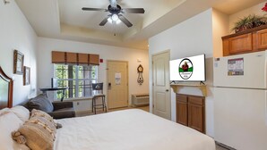 A bedroom with a bed, a ceiling fan, a window, a desk, and a refrigerator. - Branson Retreat • Golf View, Kitchenette, & Ticket/Golf Discounts (Branson)