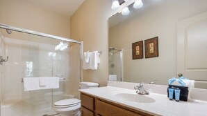 A modern bathroom with a glass-enclosed shower, a white toilet, a vanity with a sink, and a large mirror. - Branson Retreat • Golf View, Kitchenette, & Ticket/Golf Discounts (Branson)
