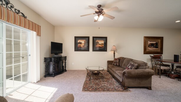 A living room with a sofa, coffee table, and a ceiling fan. There are framed pictures on the wall and a lamp on a side table. - Central Branson Stay • 1BR/1BA Condo • Walk-In Access (Branson)