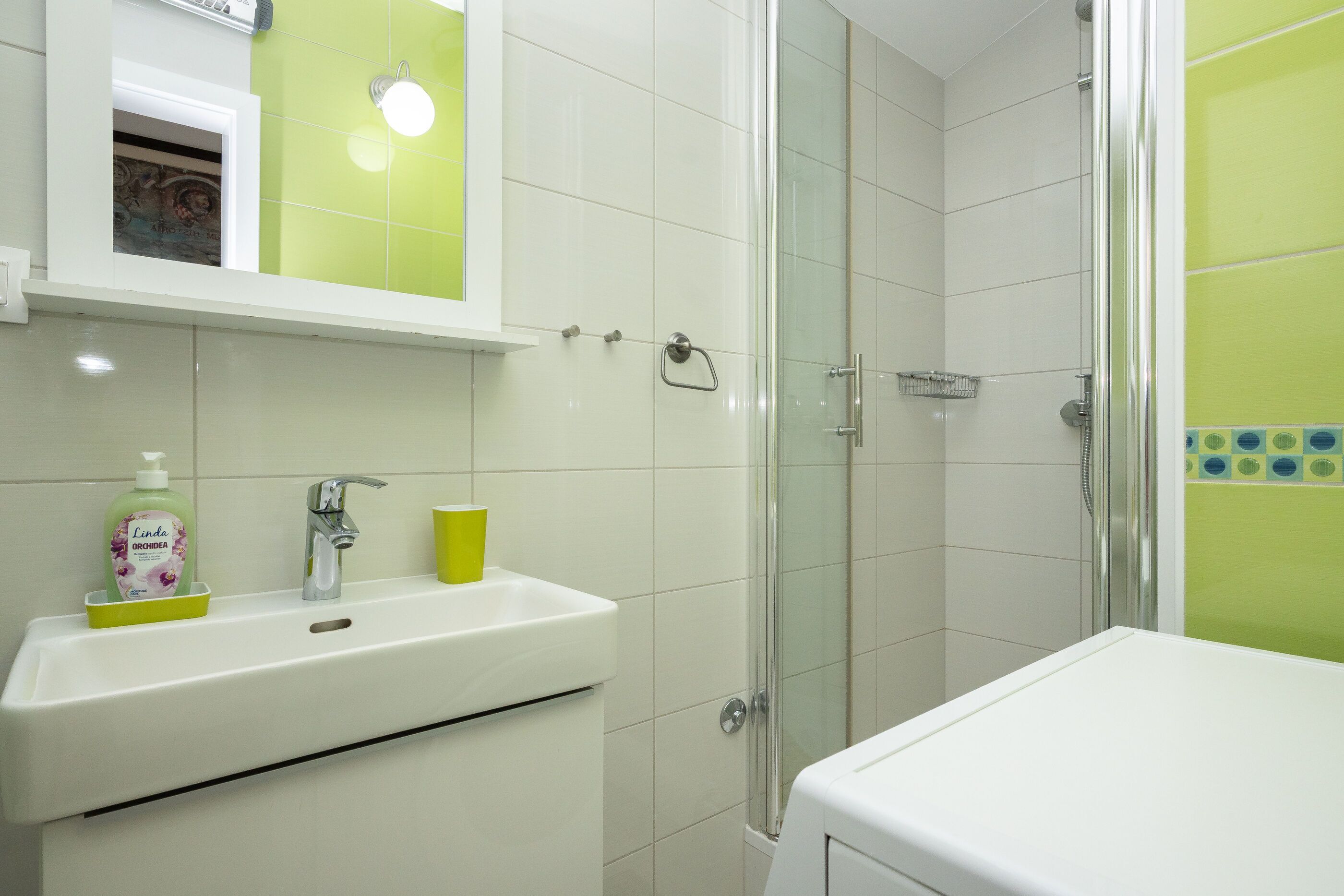 Un baño con lavamanos, espejo y ducha.