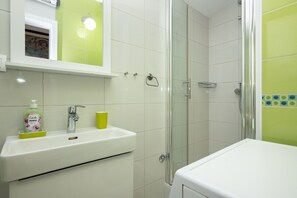 Un baño con lavamanos, espejo y ducha.