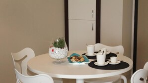 A round table with white chairs, a glass vase with flowers, a plate of cookies, and white cups and saucers. - 2-bedroom DELUXE apartment (Rimini)