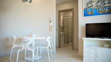 Een moderne kamer met een eettafel en stoelen, een televisie en een douche.