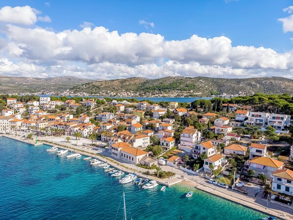 A coastal town with buildings, a marina, and a clear blue sea.