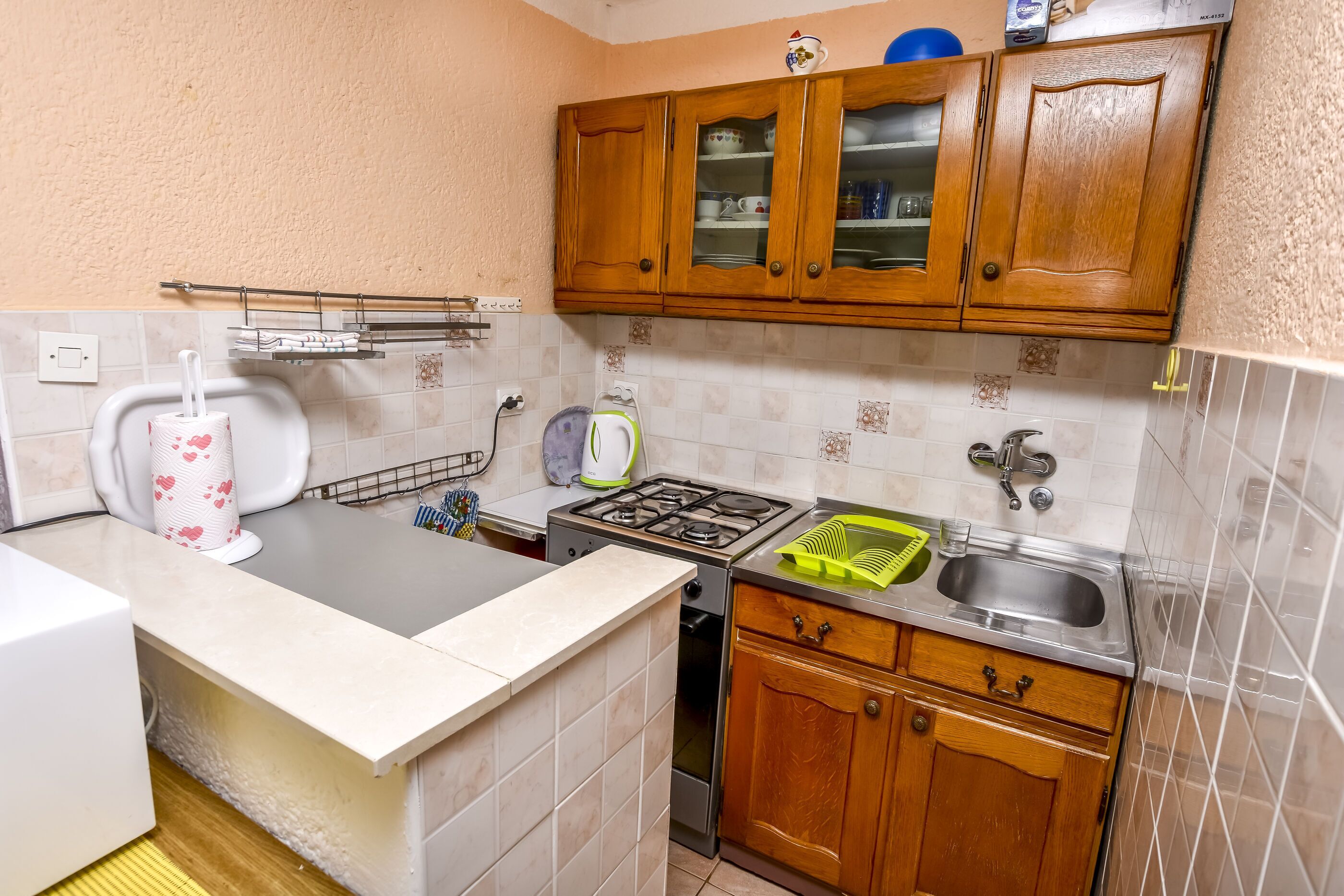 Cozinha compacta com armários de madeira, fogão a gás, pia e bancada.