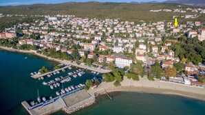 Ett flygbildsfoto av en kuststad med en småbåtshamn, bostadshus och en strand.