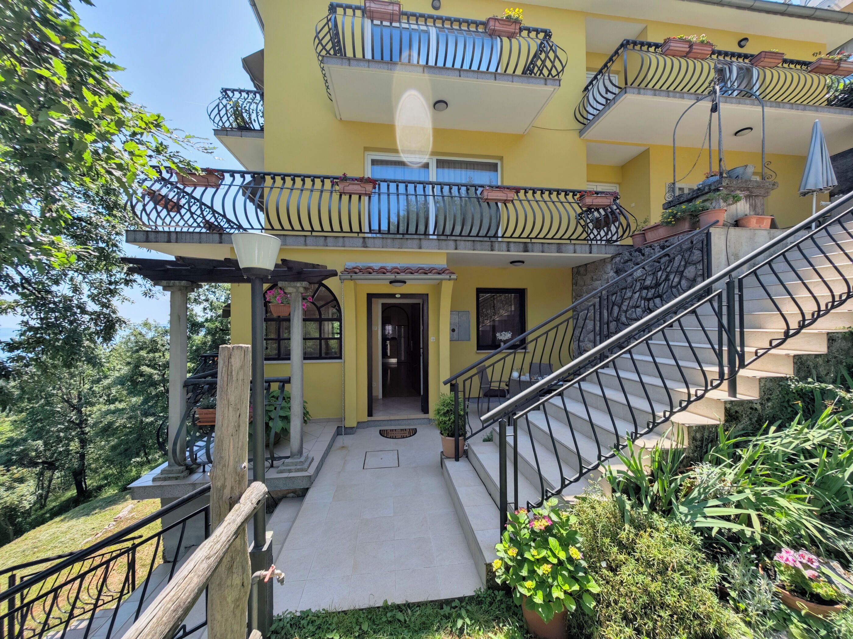 A multi-story building with balconies, a staircase, and a garden area.